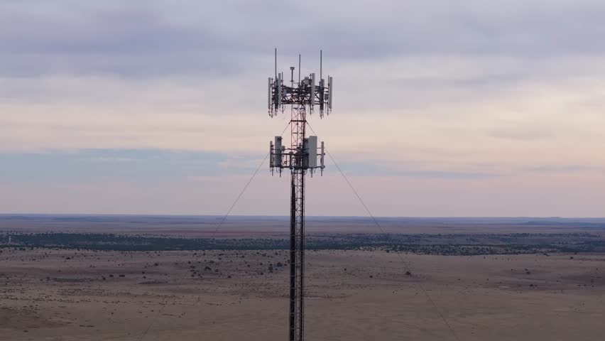 A cell tower in a remote Texas landscape with a vast desert stretching out beneath it