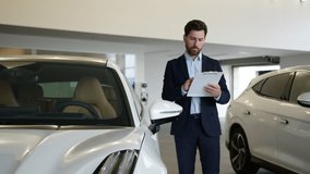 Caucasian adult man holding clipboard document salesman analyzing dealer showroom auto automobile new car rental service male guy consultant manager salon insurance credit buying vehicle writing check - Powered by Shutterstock - Get 15% off with code: PIKWIZARD15