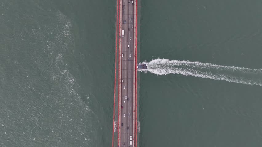 Passenger ferry sails across Golden Gate strait under highway on suspension bridge