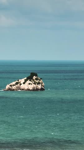 A small rocky outcrop appears in the middle of the vibrant sea. Ko Samui, Thailand.