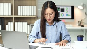 Professional businesswoman analyzing financial statistics at office desk, wearing blue shirt and glasses while reviewing accounting documents and calculator data - Powered by Shutterstock - Get 15% off with code: PIKWIZARD15