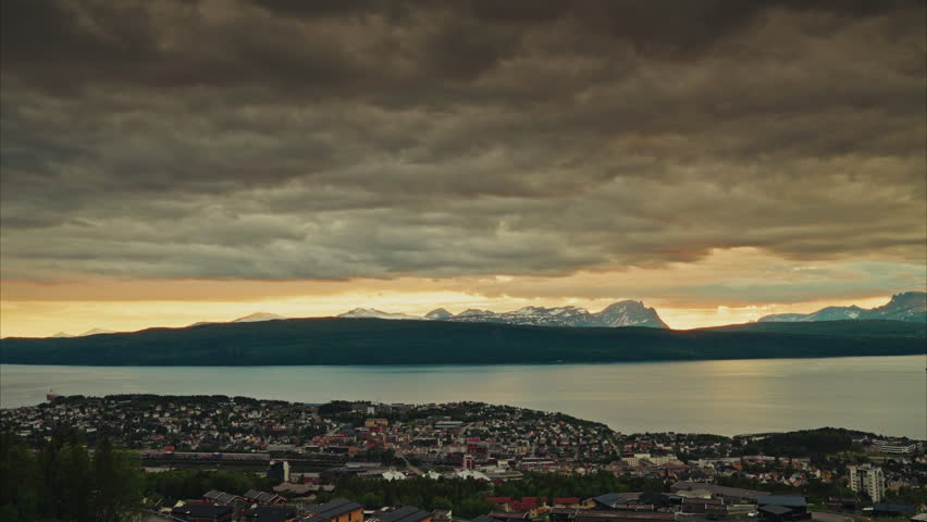 Time lapse of the midnight sunset over the Norwegian fjords in Narvik.
View of the dramatic traveling clouds at golden hour. Picturesque nordic landscape.