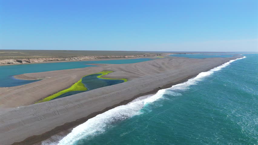 Waves break on sandbar near the sunny, arid shore of the Valdes Peninsula, Argentina