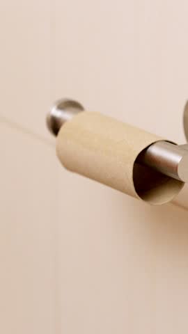 Man replacing empty toilet paper roll in bathroom