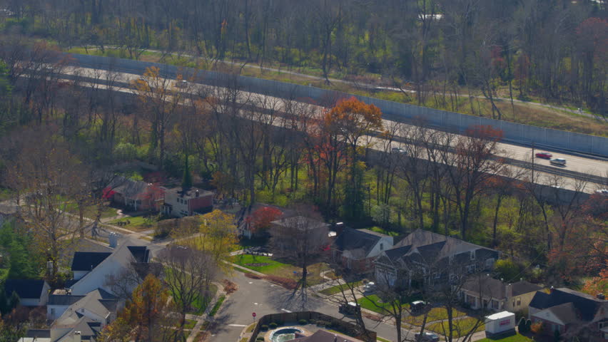 High-quality aerial over a picturesque neighborhood street with nice houses in fall in St. Louis, Missouri. Features vibrant foliage, Highway 40 beyond the subdivision, and smooth tilts and slides.
