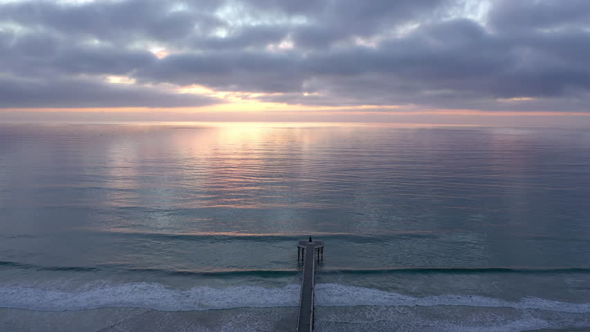 Aerial drone shot of Pacific Ocean and Crystal Pier in Pacific Beach San Diego California at sunset, drone backwards