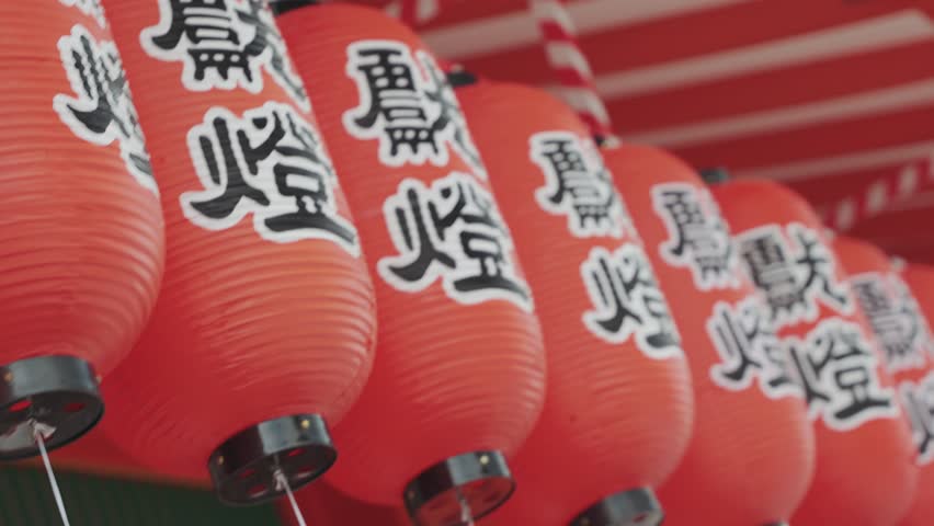 A close-up video capturing the intricate details of glowing red lanterns adorned with Japanese writings at a temple, showcasing the spiritual ambiance and rich cultural heritage of the sacred site.