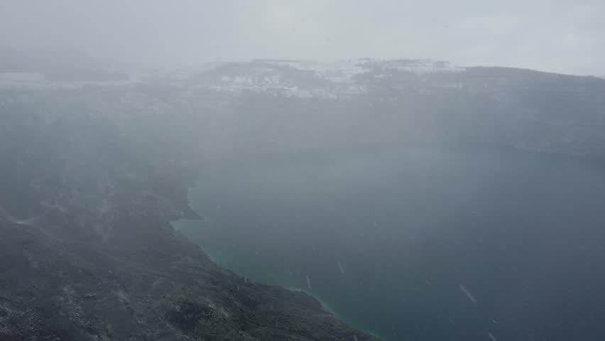 Aerial drone shot of Thetford Mines during snowstorm with lake and snowfall in Quebec, Canada