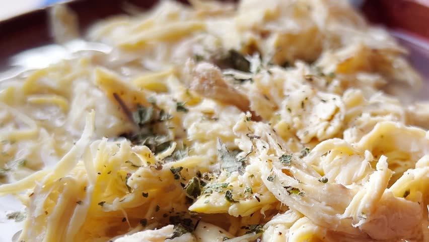 Chicken pozole featuring shredded chicken simmered in smoky chipotle tomato sauce, serving as a flavorful option for tacos, tostadas, or enchiladas in Mexican cuisine