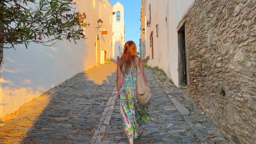 Woman Walking Through the Charming Streets of Monsaraz, Portugal, at Sunset.