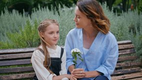 Single mom kissing daughter at park bench closeup. Small child girl gentle mother enjoying tender flower bonding at green lush nature. Adult woman showing love to kid outdoors. Motherhood concept - Powered by Shutterstock - Get 15% off with code: PIKWIZARD15