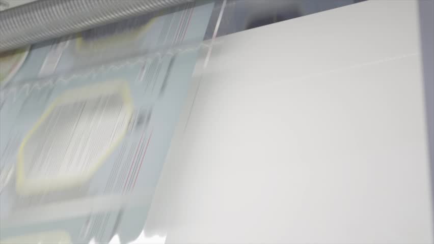 A detailed close-up shot showing the printed packaging advancing through the machine during the production process. Flat Log profile.
