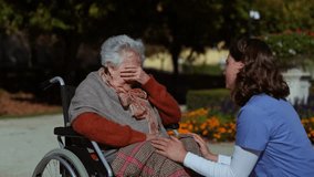 Disabled elderly woman in wheelchair talking with her nurse, sharing her problems with female caregiver. - Powered by Shutterstock - Get 15% off with code: PIKWIZARD15