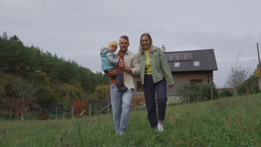 Family house with rooftop solar panels. Young family in front of solar-powered home.