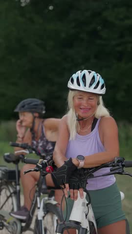 Video of beautiful senior cyclist on bike tour in nature with friends. Older woman on low impact route riding electric bikes.