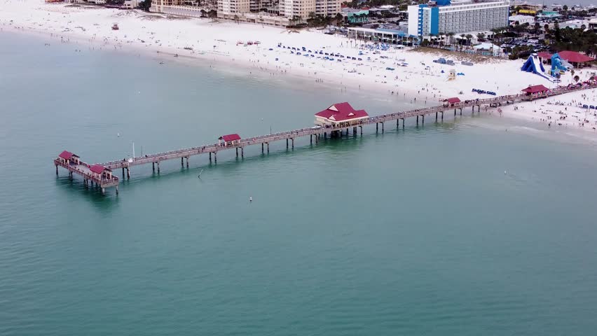 Pier 60 at Clearwater Beach, Florida, United States. Aerial side-angle shot of the famous pier with beachgoers, crystal-clear waters, and a perfect summer vibe.