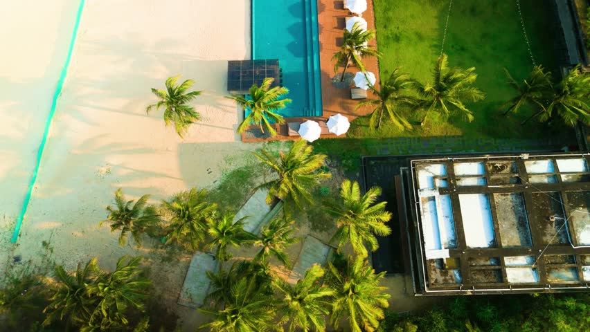 Aerial perspective revealing luxurious tropical resort with expansive swimming pool, white sandy beach, verdant landscaping, solar panels highlighting eco friendly hospitality design