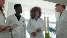 Group of scientists in lab coats conducting experiment, observing chemical reaction in graduated cylinder, senior scientist explaining process to younger colleagues - Powered by Shutterstock - Get 15% off with code: PIKWIZARD15