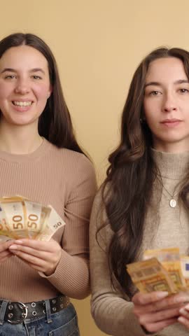 Two women celebrating with euro banknotes in joyful mood