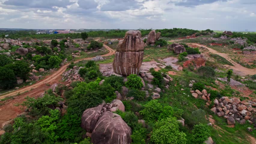 Granite hill with trees, sand road way and rainy clouds at telangana, india. day time, push in, drone shot, 4k.