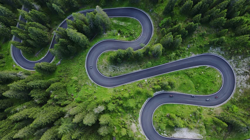 Top-down aerial view of winding mountain road weaving, lush green landscapes