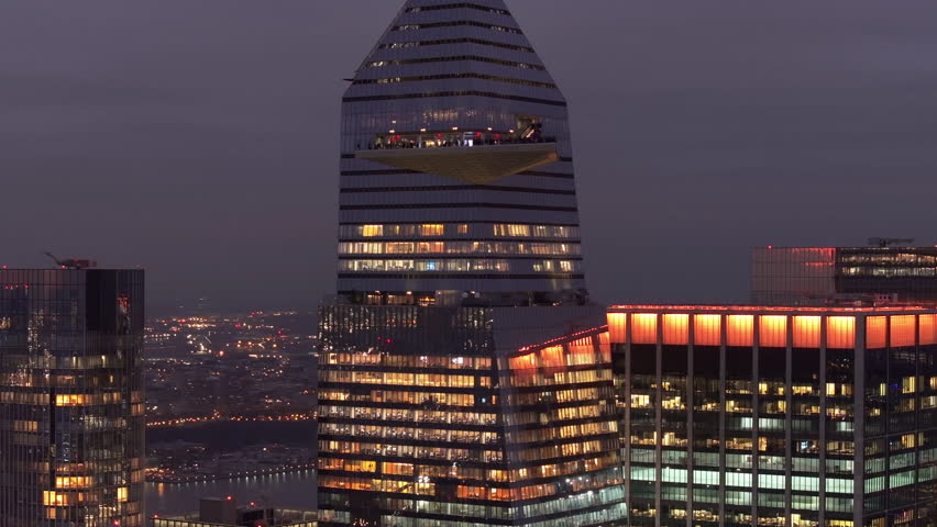 Tourists watch Manhattan skyline from Edge NYC Observation Deck in Hudson Yards, capturing metropolitan vibrancy during twilight hours
