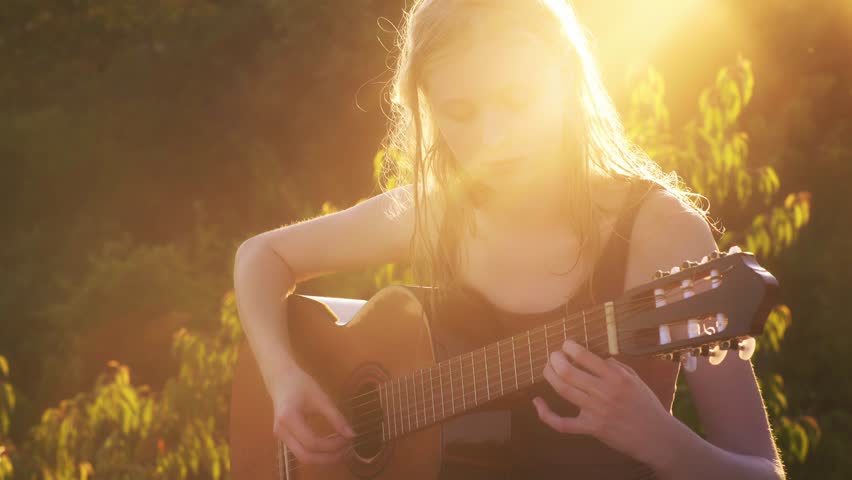 Girl playing Guitar on sunset. Romantic woman with a guitar. Beautiful singer outdoors. Talented guitarist. Sensual musician. Sensual woman with a guitar. Artistic woman playing music. Female