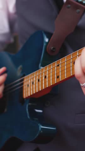
Concert view of an electric guitar player with vocalist and rock band performing in a club, male musician guitarist on stage with audience in a crowded concert show club hall arena, hands on guitar