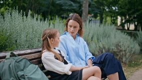 Woman schoolgirl sitting bench talking together. Middle aged beautiful mother having conversation with small cute daughter at park alley. Tender family relaxing at greenery nature. People lifestyle - Powered by Shutterstock - Get 15% off with code: PIKWIZARD15
