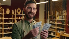 Rich wealthy happy Caucasian man male businessman guy small business owner entrepreneur potter apron counting money dollars winning cash salary finance wage budget payment wealth inside pottery store - Powered by Shutterstock - Get 15% off with code: PIKWIZARD15