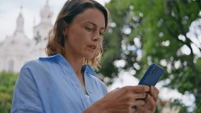 Focused woman chatting smartphone at summer park closeup. Middle aged beautiful lady answering message holding mobile phone at city. Serious female using cellphone waiting friend at greenery garden - Powered by Shutterstock - Get 15% off with code: PIKWIZARD15