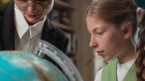 Studying geography Caucasian woman female professor teacher teaching little girl student school kid child pupil learner learn world map holding magnifier exploring globe earth indoor library classroom - Powered by Shutterstock - Get 15% off with code: PIKWIZARD15