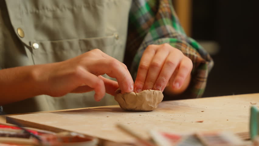 Close up unrecognizable Caucasian little girl artist sculptor ceramist child school kid student daughter children hands kneading clay material shaping modeling sculpture ceramic pottery indoor studio