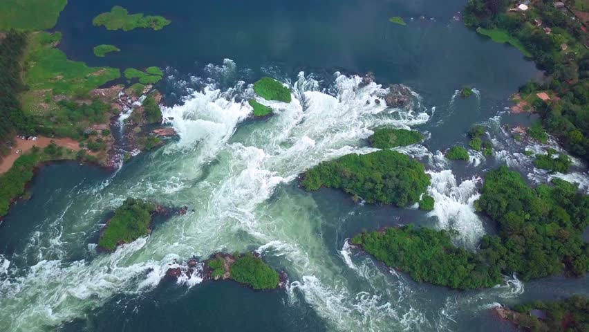 Drone pull out showcasing the majestic panorama of the River Nile as it flows through Uganda, Africa, creating breathtaking waterfalls and lush green islands, a testament to the raw beauty of nature