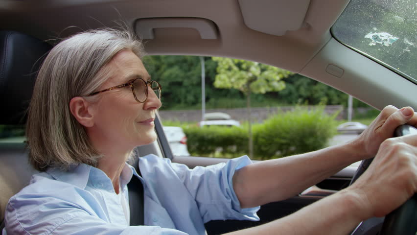Satisfied happy Caucasian woman retiree female senior tourist pensioner car driver riding in automobile driving steer vehicle auto driveway opened window wind fresh air wellbeing travelling retirement