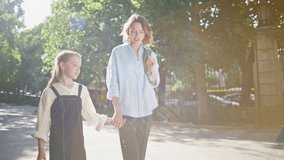 Mom kid strolling greenery park communicating together. Tender lady parent small girl going home after school lesson. Gentle mother carrying backpack enjoying time with daughter at sunlight alley - Powered by Shutterstock - Get 15% off with code: PIKWIZARD15