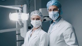 Two healthcare professionals, dressed in surgical attire, stand in a modern dental clinic. They wear masks and protective gear, ready to assist patients with dental care. - Powered by Shutterstock - Get 15% off with code: PIKWIZARD15
