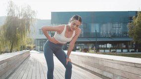 Young Caucasian runner suffering from abdominal pain during a run in urban city park on sunny day. Sad woman keeps her hand on her stomach. Girl has poisoning, constipation, spasms or menstruation. - Powered by Shutterstock - Get 15% off with code: PIKWIZARD15