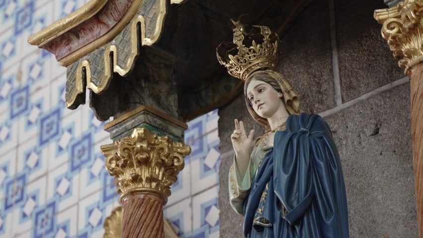 Ornate statue of the Virgin Mary wearing a crown in a decorated church interior