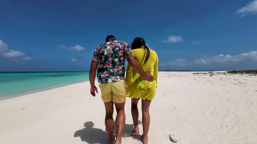 Romantic couple walking along a sandy path in Cayo de Agua Los Roques low angle