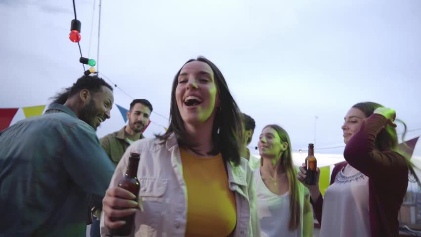 Point of view of a happy Caucasian woman dancing to the camera at a rooftop party.