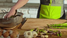 Woman slicing asparagus for cooking on kitchen table. Frying it in pan. Closeup hands. Slow camera panning. - Powered by Shutterstock - Get 15% off with code: PIKWIZARD15