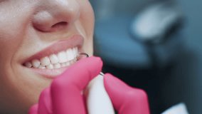 A patient smiles while receiving dental care in a modern clinic. The dentist uses specialized tools to check the patient's teeth, ensuring a comfortable and professional experience. - Powered by Shutterstock - Get 15% off with code: PIKWIZARD15