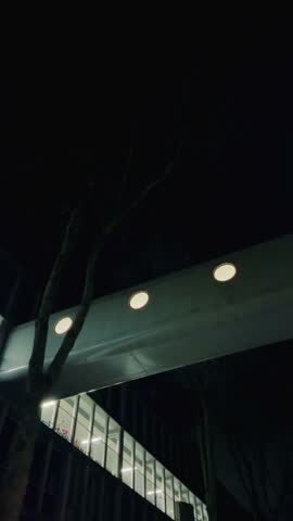 Close-up of modern pedestrian bridge in Amsterdam Noord, featuring circular embedded lights against the night sky. Minimalistic and futuristic design highlights urban infrastructure in Netherlands