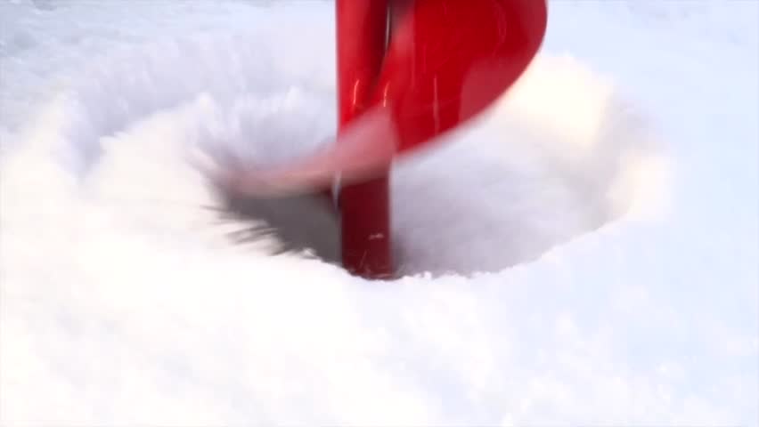 Red Ice Auger Boring Hole In Frozen Water For Ice Fishing In Winter. closeup shot