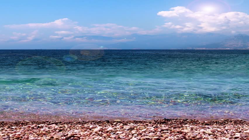 sea waves fall on a pebble beach under a sunny sky
