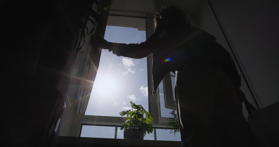 Woman closes window, unknown silhouette. Sunshine streaming through open window. Cinematic video, enjoying morning, pure tranquility, slow motion, clean fresh air and peaceful ambiance.