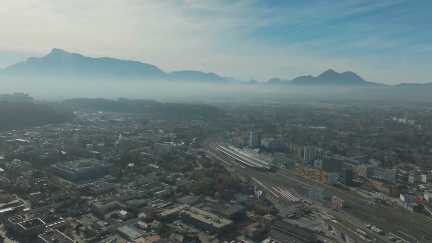 Salzburg Drone, Austria. Aerial View of Central Train Station and Cityscape and misty mountains