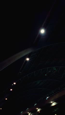 Dark industrial-style roof structure illuminated by spotlights at night. The curved framework and symmetry create an impressive futuristic atmosphere. Location: Netherlands