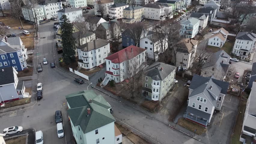 Cars on street in american neighborhood with residential Apartments. Aerial top down flyover shot. Colored roofs of homes in Town of Massachusetts.